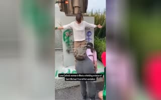 Heroic Woman Protects The Statue Of Saint Micheal From Leftist Activists Trying To Destroy It